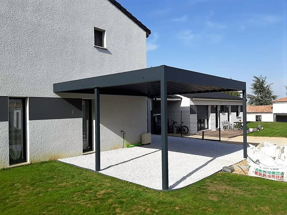 Pergola bioclimatique grise devant une maison moderne avec patio en gravier blanc et pelouse. Numéro: 05 61 72 80 80.