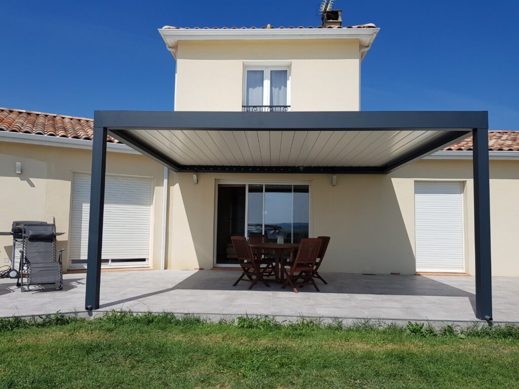 Maison avec terrasse et pergola bioclimatique moderne couvrant un espace repas extérieur. Mobilier de jardin, barbecue et pelouse.