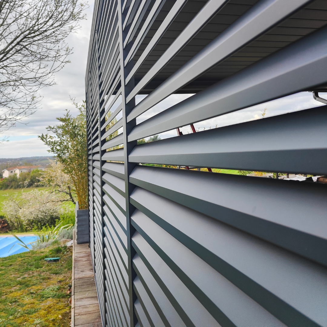Vue rapprochée d'un claustra design gris à lames horizontales dans un espace extérieur avec piscine.