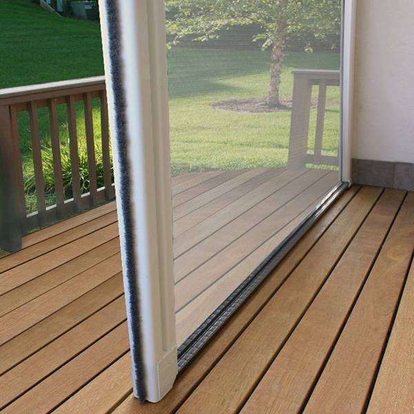 Moustiquaire rétractable pour porte coulissante sur une terrasse en bois. Vue rapprochée du rail et du joint brosse.