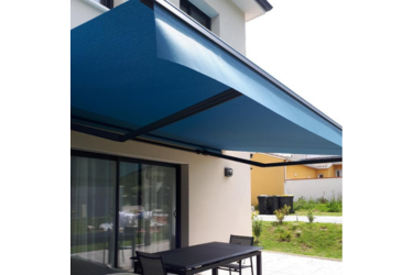 Grand store banne bleu sur une terrasse de maison moderne avec table et chaises. Protection solaire pour l'extérieur.
