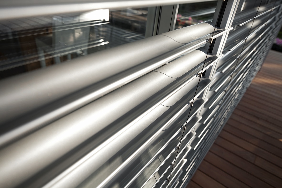 Brise-soleil orientable en aluminium argenté pour protection solaire efficace d'une baie vitrée moderne.