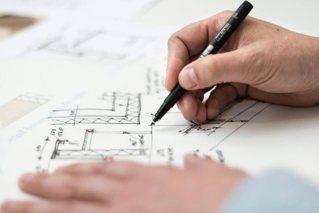 Croquis d'Architecture : Dessin à la Main de Plans Techniques Close-up of hand drawing intricate technical designs on blueprint with pen, ideal for engineering or architecture themes.