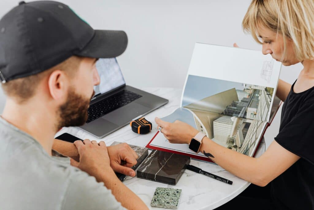 Architectes d'Intérieur : Projet Design et Échantillons Two interior designers discussing architectural plans in an office setting.