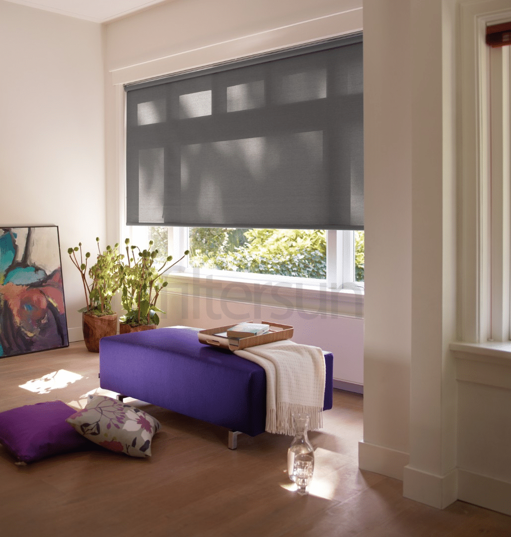 Store enrouleur gris tamisant sur une grande fenêtre, banc violet et plantes vertes dans un salon élégant.