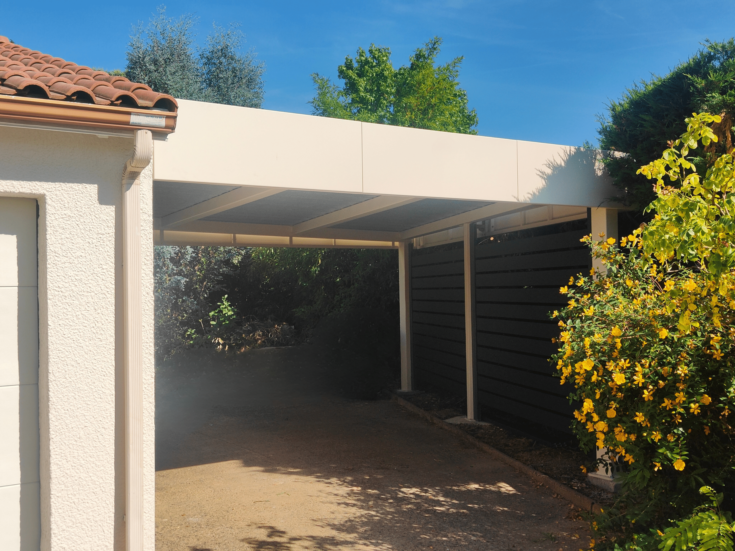 Carport aluminium sur mesure, moderne, à toit plat et bandeaux périphériques.
