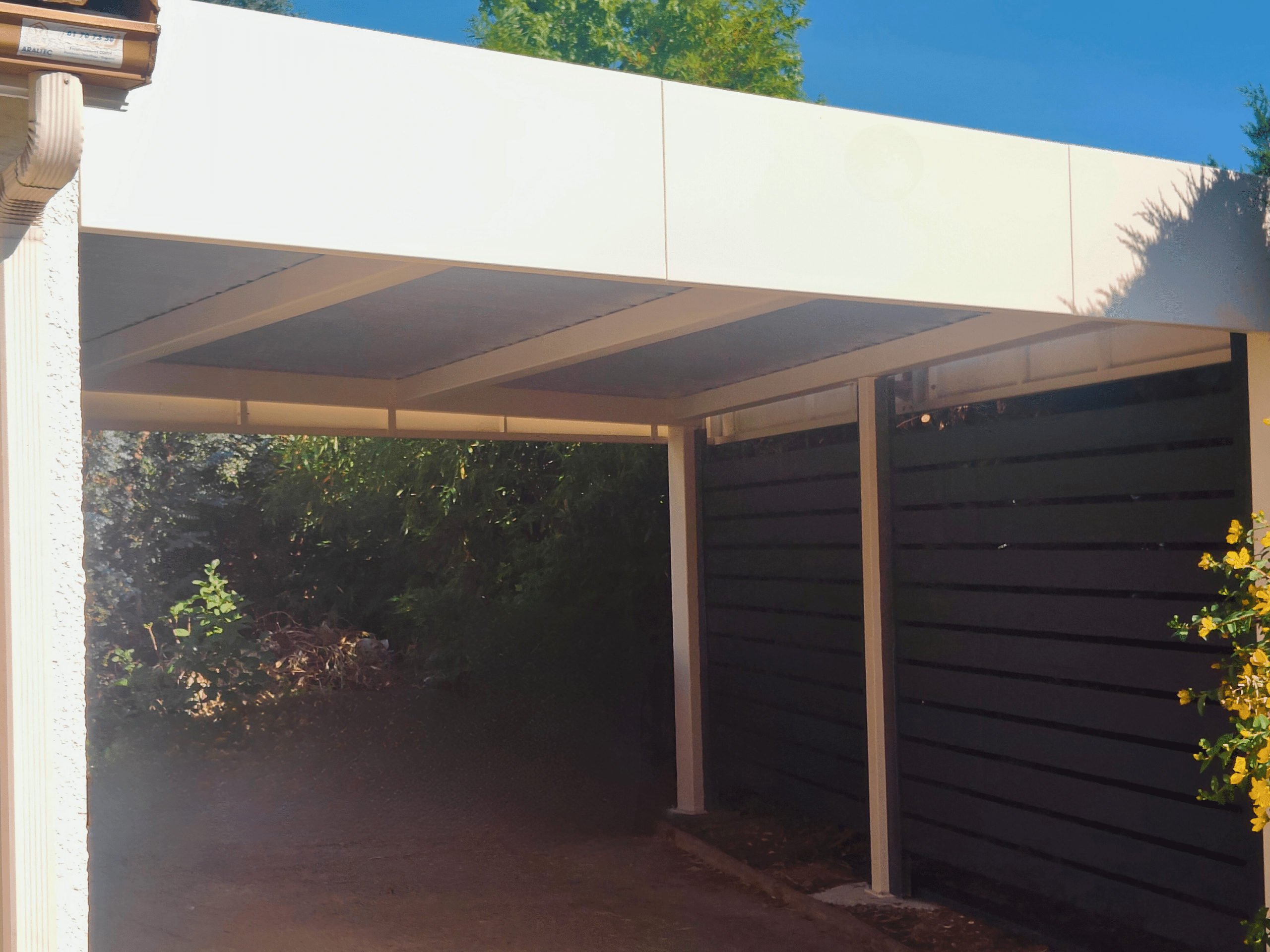 Carport aluminium sur mesure, moderne, à toit plat et bandeaux périphériques.