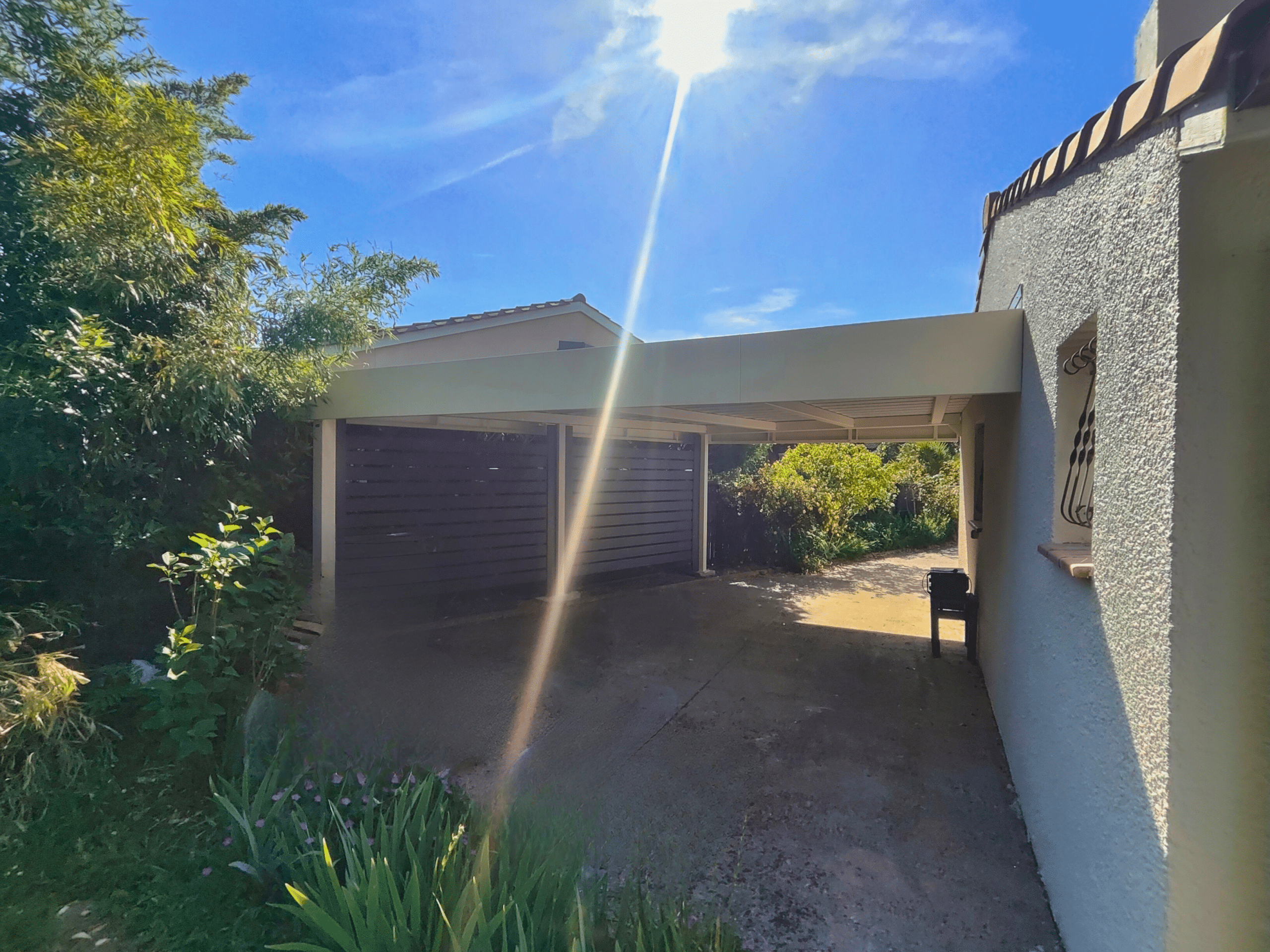 Carport aluminium sur mesure, moderne, à toit plat et bandeaux périphériques.