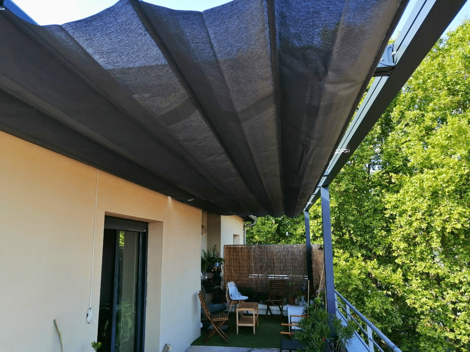 Pergola Vélum avec toile Soltis 92 déployée, à manoeuvre manuelle par cordon, sur terrasse de 10 mètres de long.
