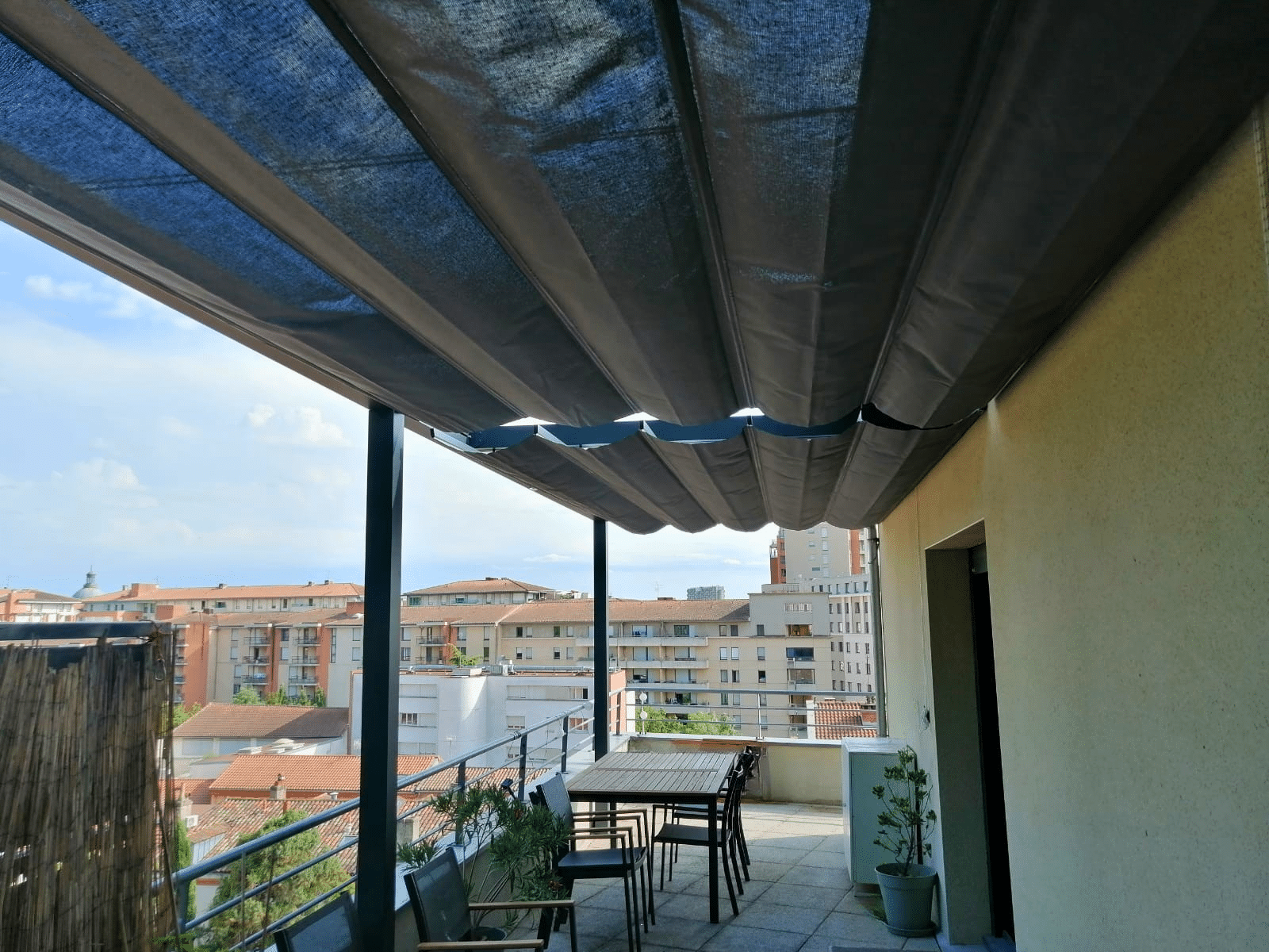 Terrasse urbaine avec pergola vélum à toile rétractable grise, sur mesure.