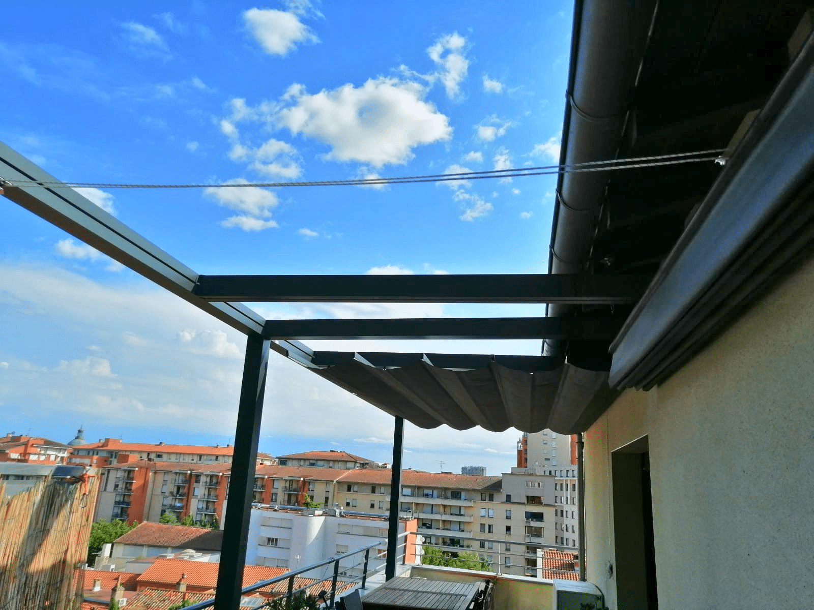 Pergola Vélum avec toile Soltis 92, à manoeuvre manuelle par cordon, sur terrasse longue.