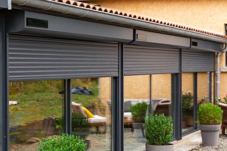 Volets roulants solaires gris anthracite sur baies vitrées d'une maison moderne.